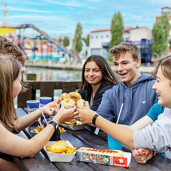 Group of friends sat at a bench eating food